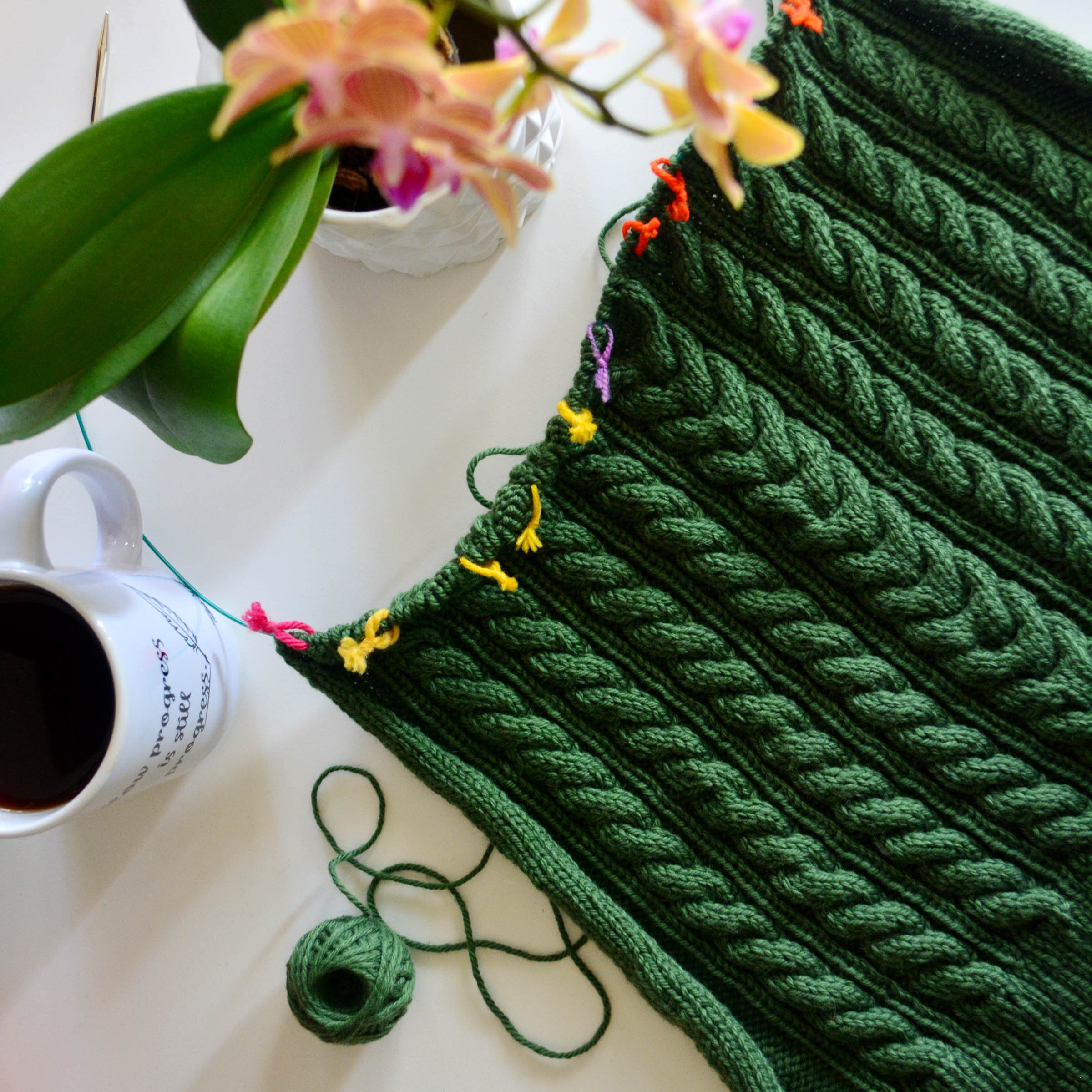 Flat lay of cabled knit project on the needles