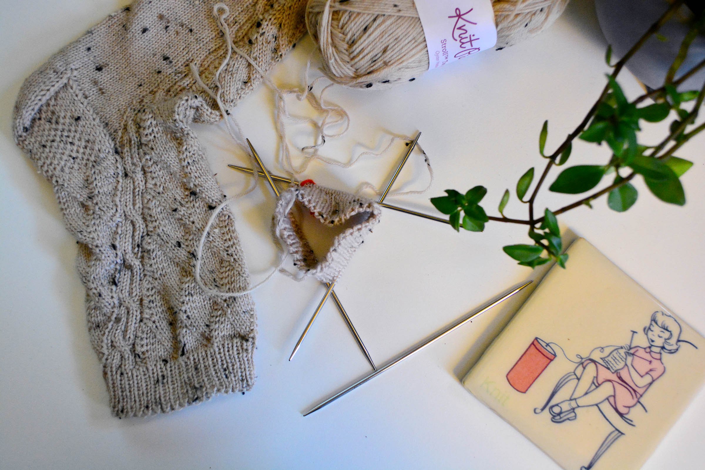 Flat lay of a completed Beanstalk Sock and a started one with only the cuff on a white desk.