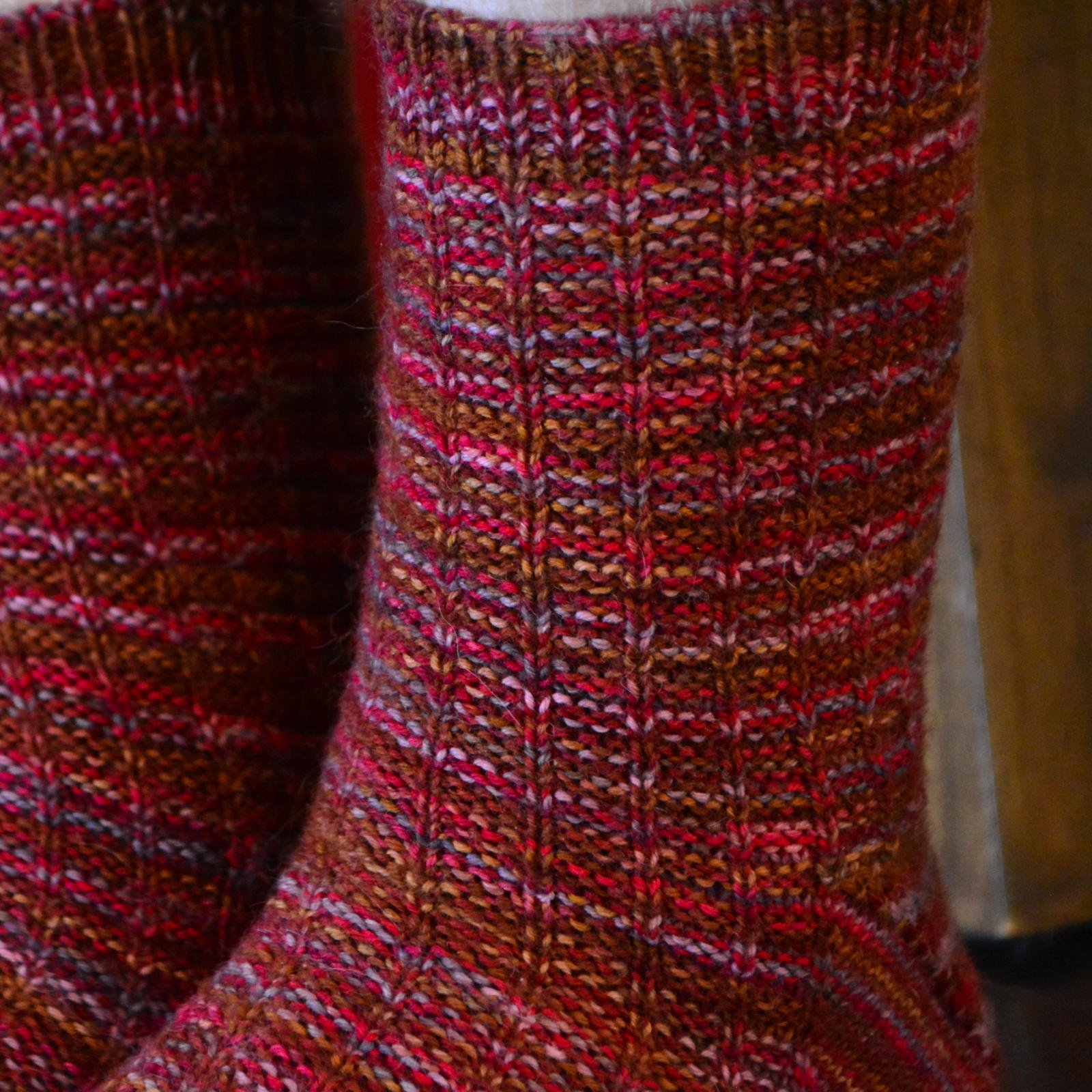 Extreme closeup of the legs and cuffs of the fingering-weight knit Adventure Socks on the model, showing the waffle weave texture and one-by-one ribbing on the one-inch cuff.