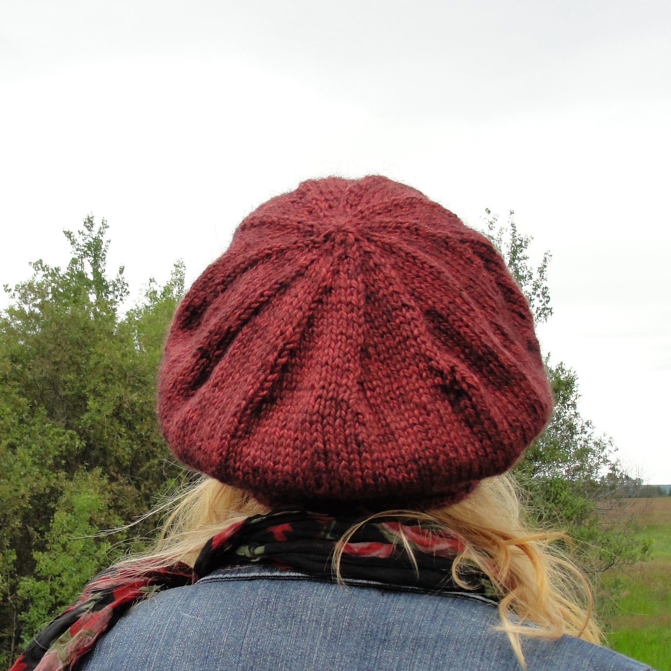 Crown decreases on a slouchy tam worn by a blond woman in front of a summer tree background.