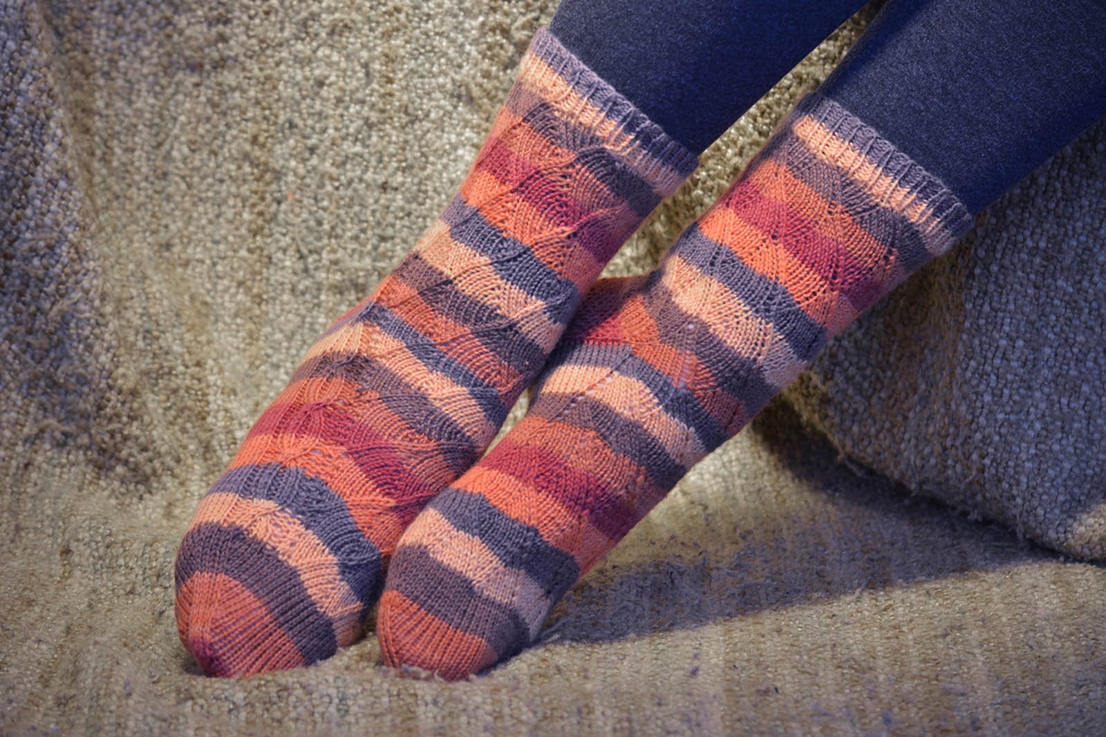 Closeup of a pair of knit socks with an unusual curved "leaf" texture and a side chain cable.