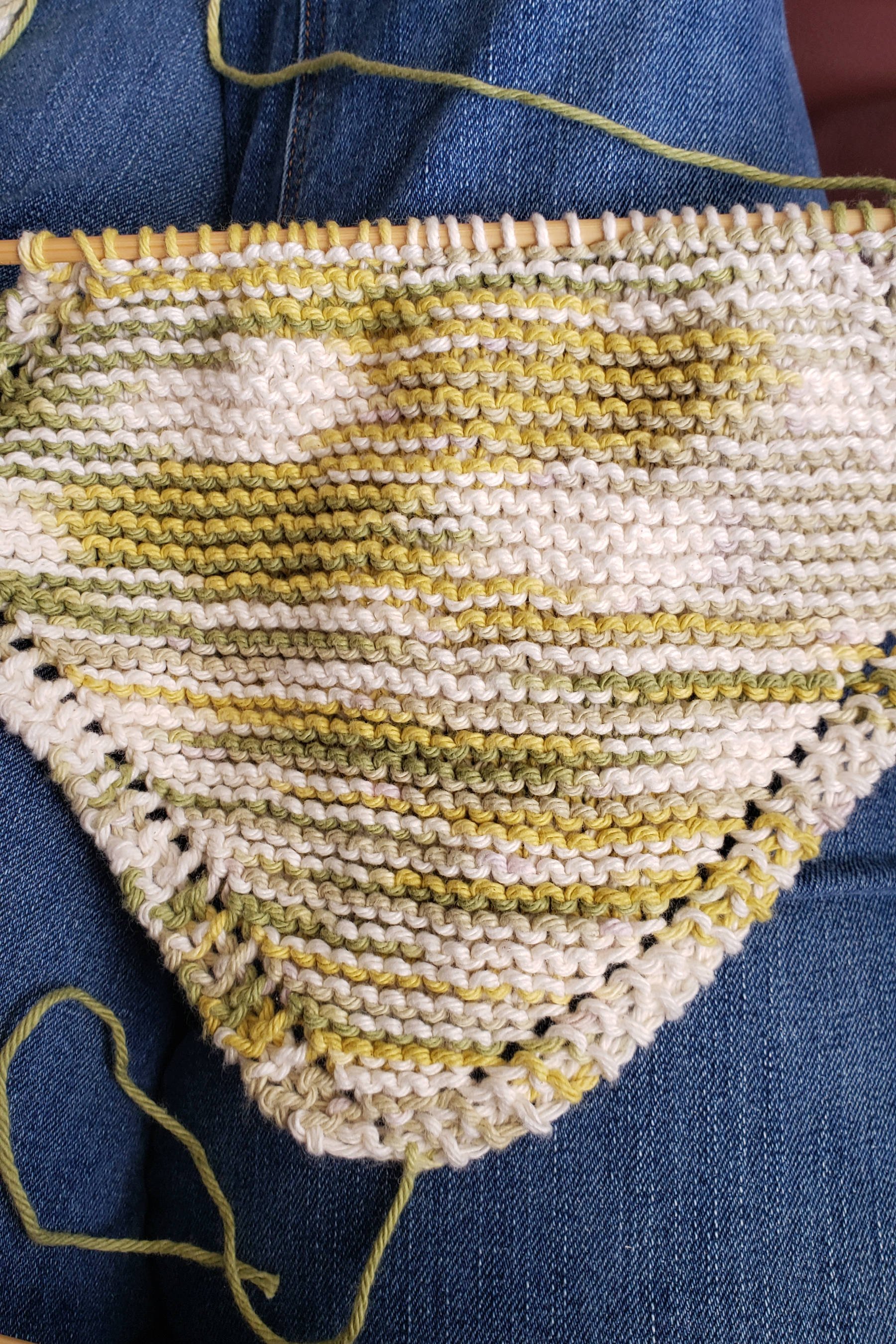 A partially finished garter stitch dishcloth on the needles knit on the bias.