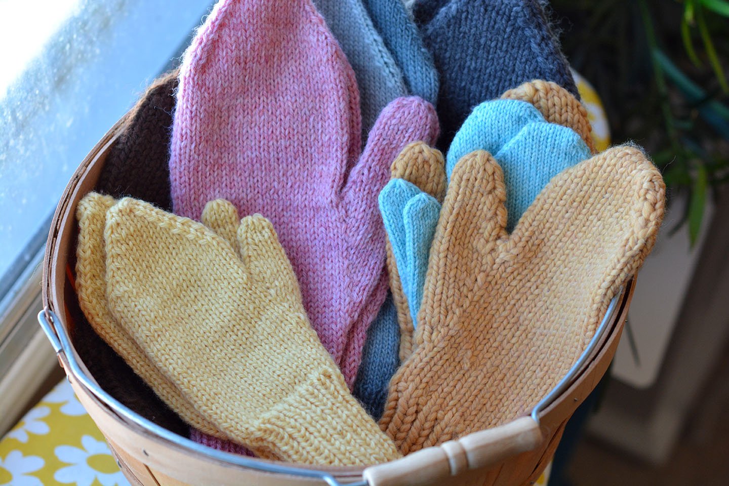 A basket of mittens of various sizes, colours, and yarn weights.